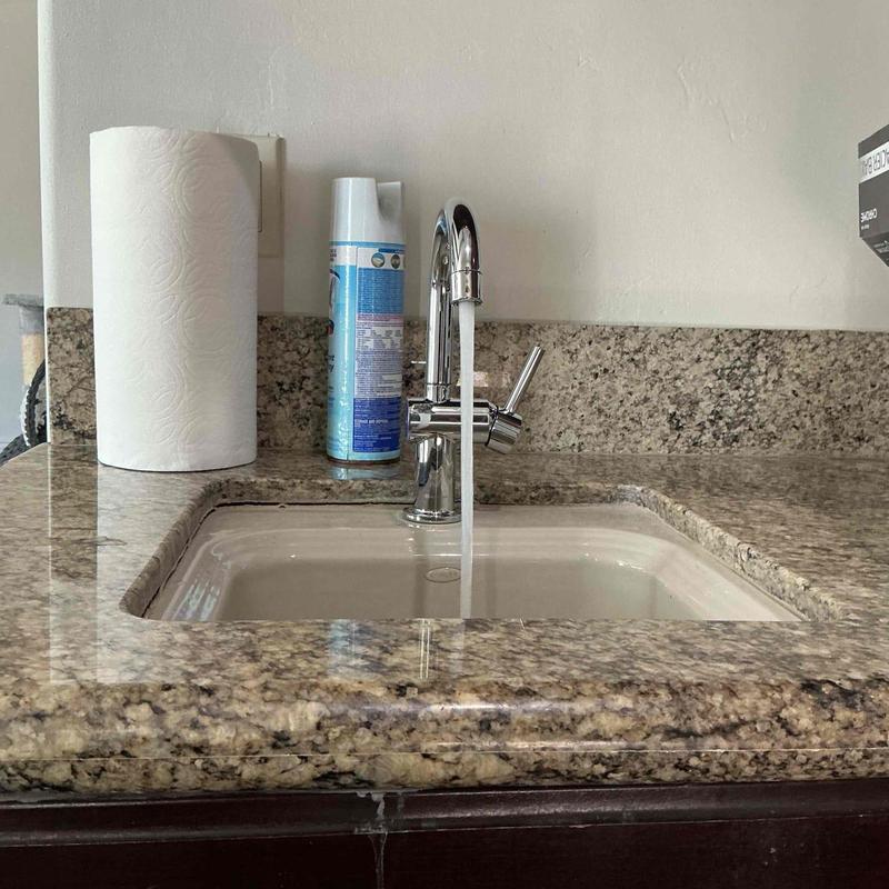 Kitchen sink faucet with running water on granite counter