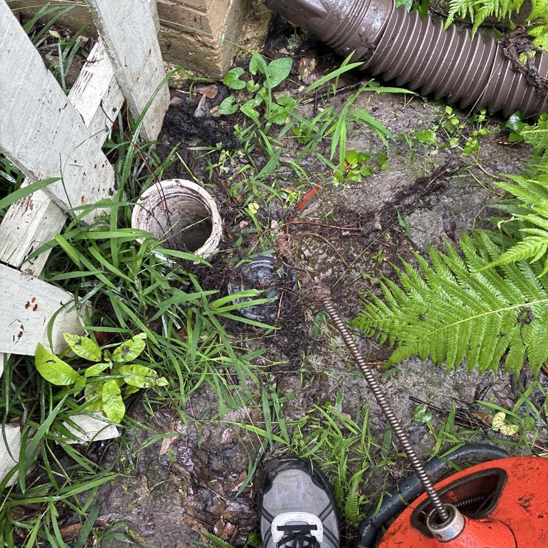 Sewer cleanout with machine auger in garden area Sewer cleanout with machine auger in garden area