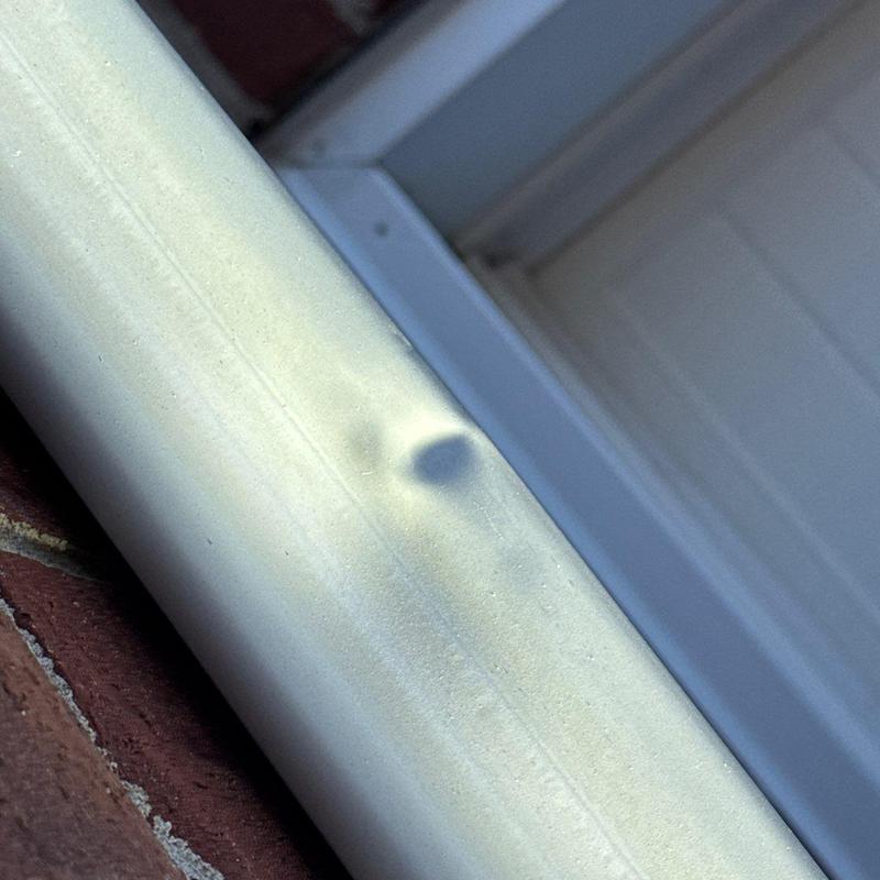 Metal flashing with hail dent damage on roof edge