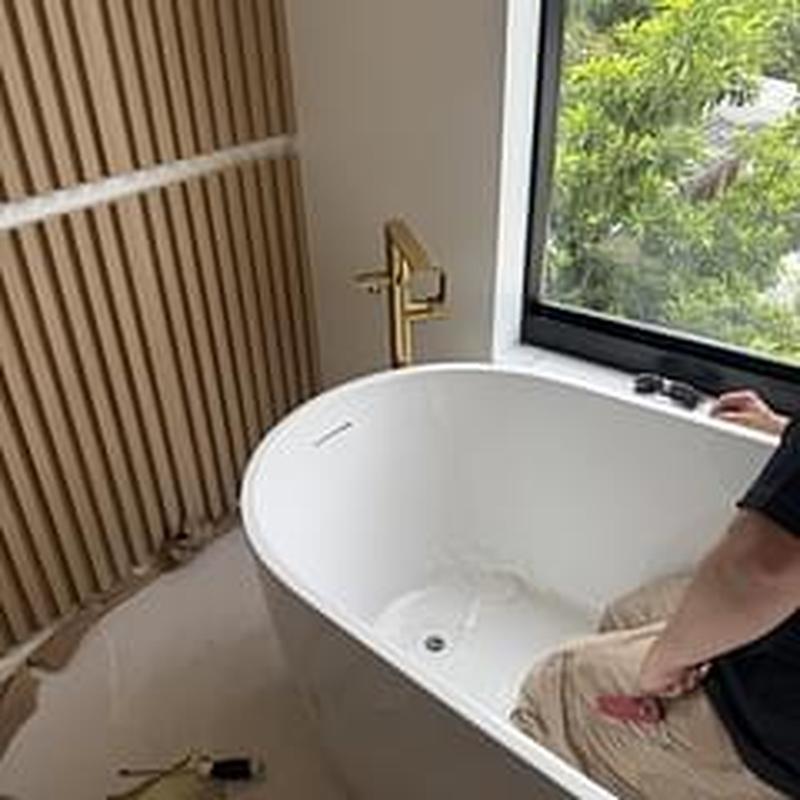 Freestanding bathtub installation with gold faucet