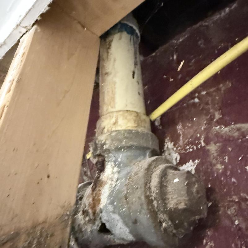 Shower valve and drain pipe with visible corrosion
