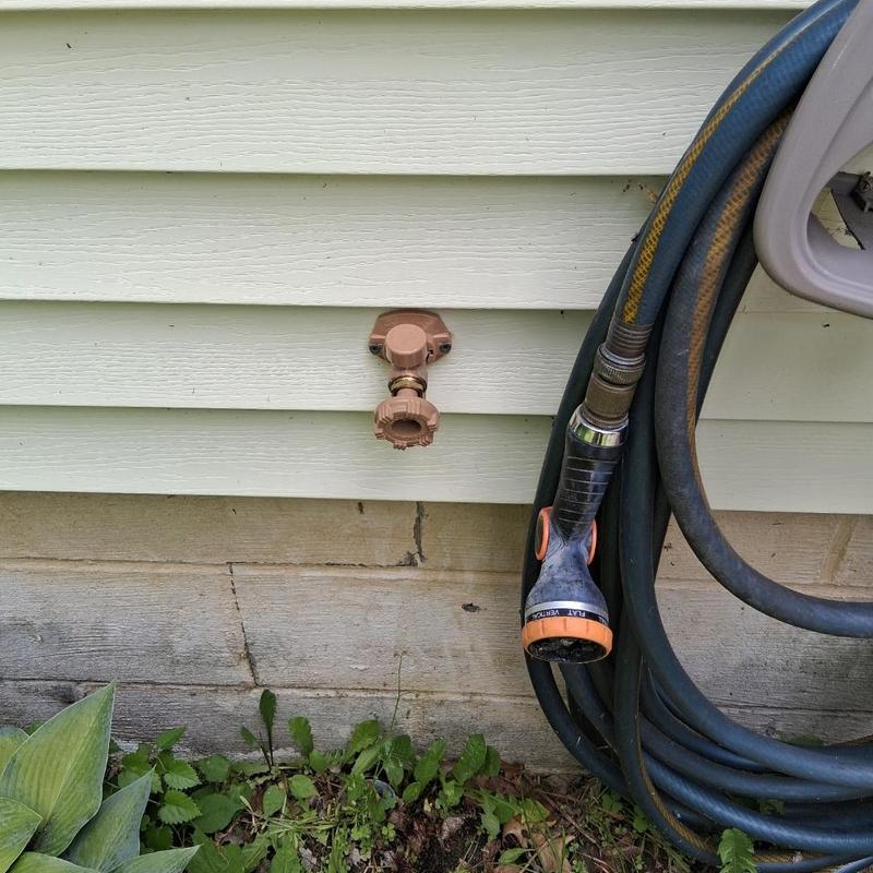 Outdoor water spigot with garden hose attached