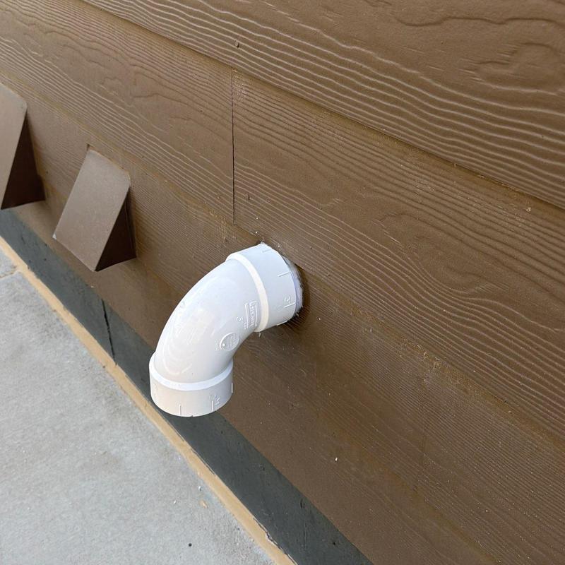 Power vent water heater PVC vent pipe elbow on exterior wall Power vent water heater PVC vent pipe elbow on exterior wall