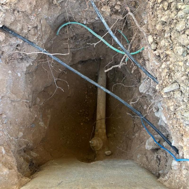 Main water line exposed in excavation hole with wiring Main water line exposed in excavation hole with wiring