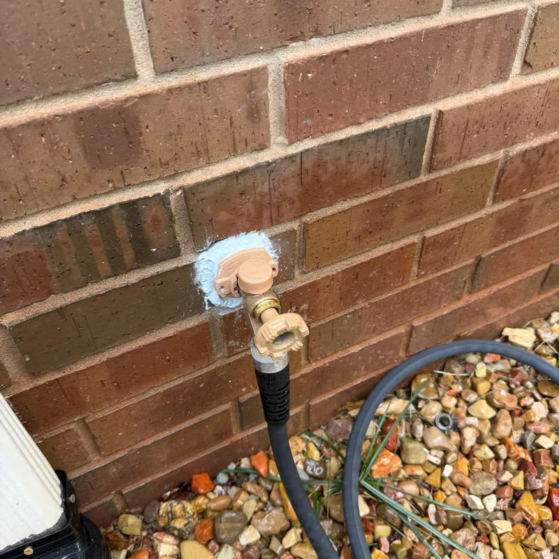 Frost proof sillcock with attached garden hose on brick wall Frost proof sillcock with attached garden hose on brick wall