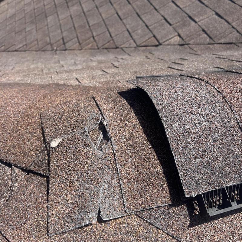Asphalt roof shingles with damage near vent pipe