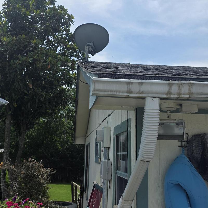 Satellite dish on roof edge with hail damage