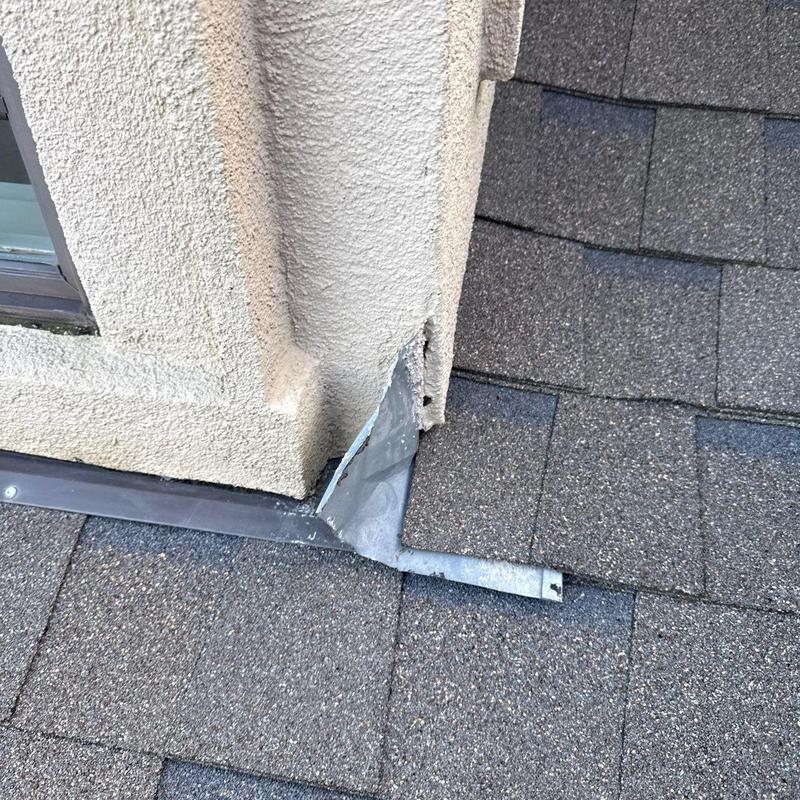 Step flashing with damaged metal near stucco wall