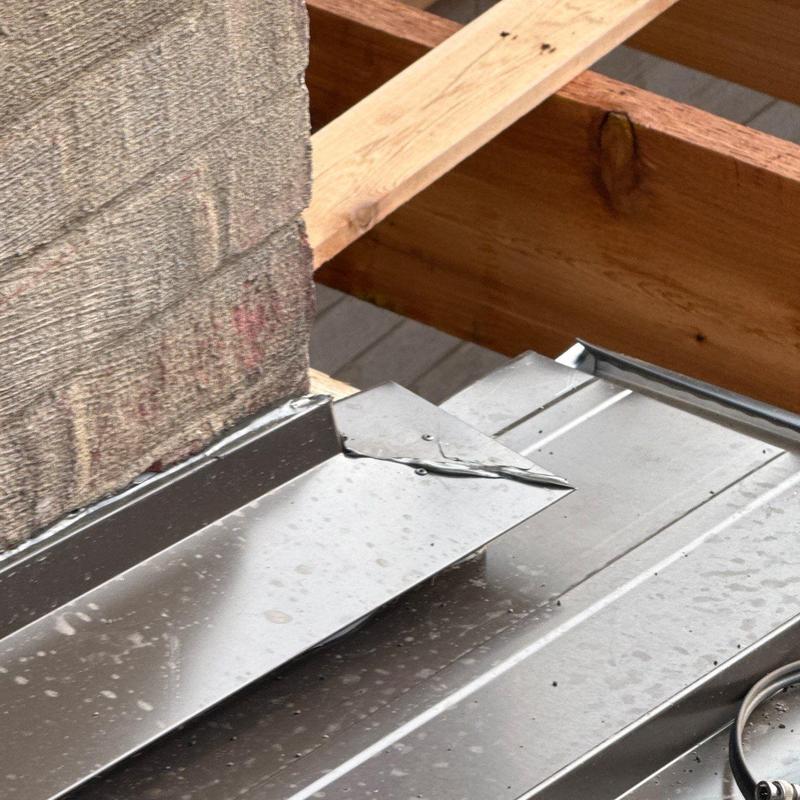 Metal roof flashing with hail damage and framing nearby