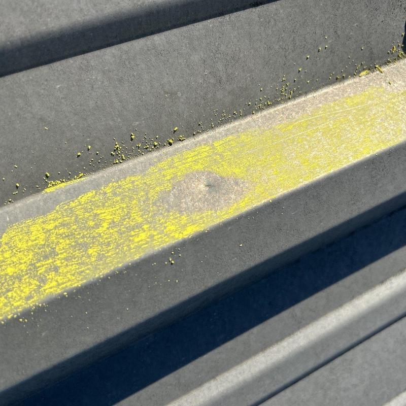 Metal commercial roof panel with hail damage mark