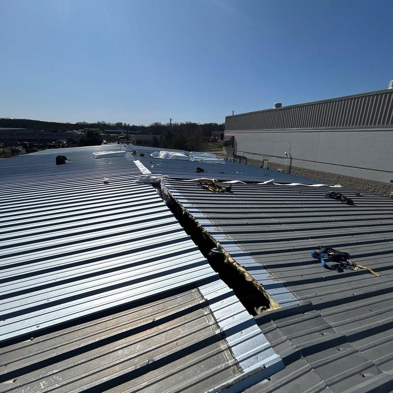 Metal commercial roof with hail damage and repair markings