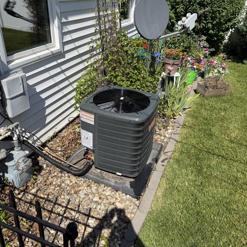 Air conditioner outdoor unit by house with garden