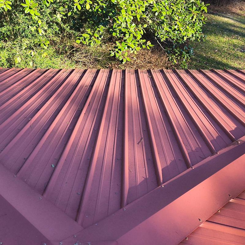 Metal roof panels with ridge flashings and greenery background