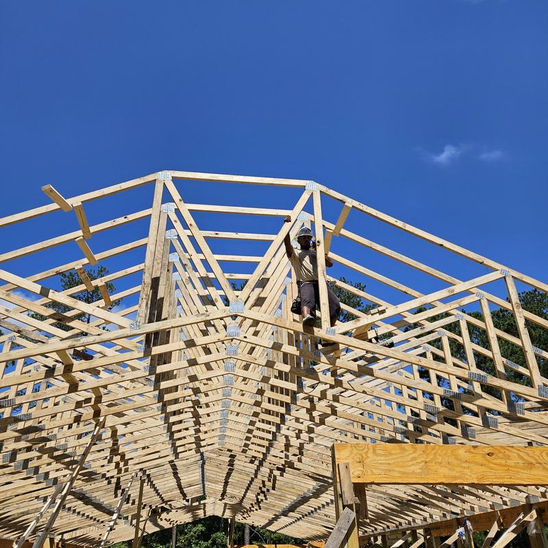 Roof truss framing installation with worker on site Roof truss framing installation with worker on site