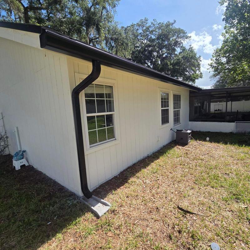 Gutter system with downspout on white siding house Gutter system with downspout on white siding house