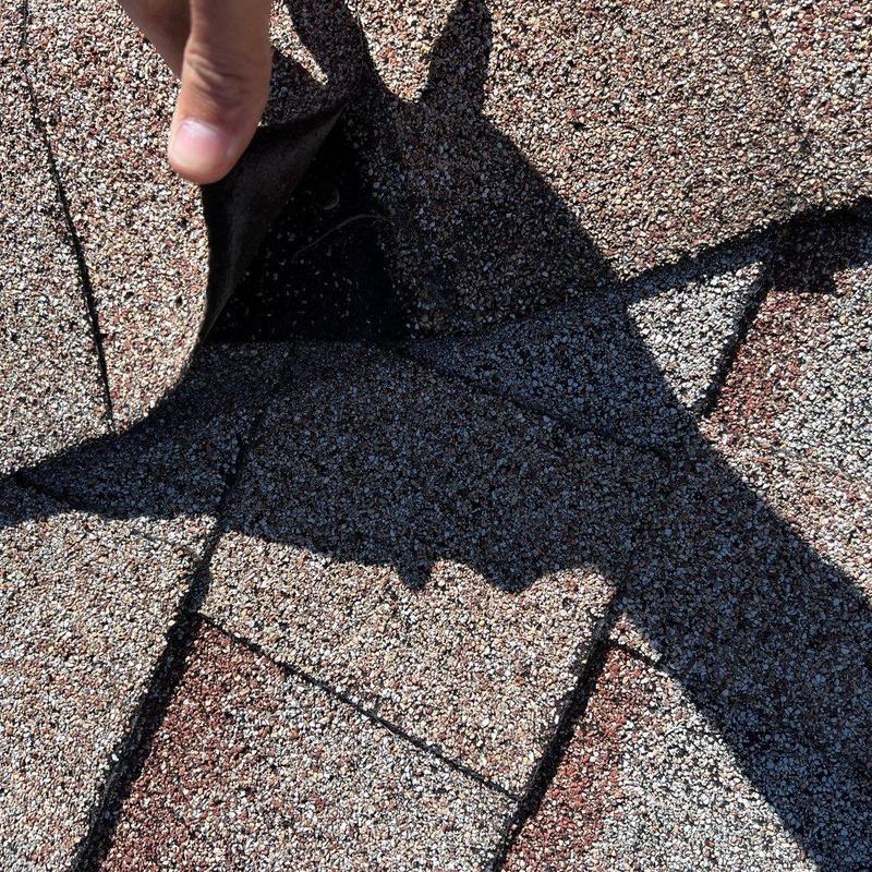 Asphalt shingle lifting showing potential leak area Asphalt shingle lifting showing potential leak area