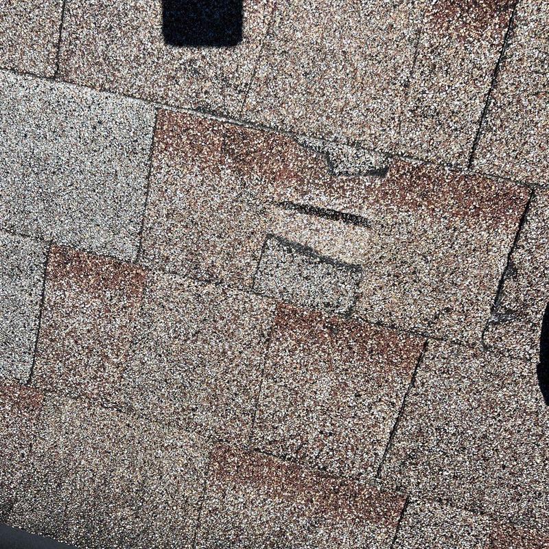 Asphalt shingle with visible wear and damage on roof Asphalt shingle with visible wear and damage on roof