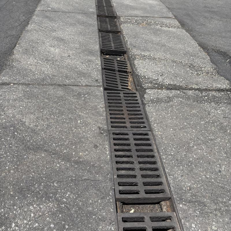 Linear drain with damaged metal grates on sidewalk Linear drain with damaged metal grates on sidewalk