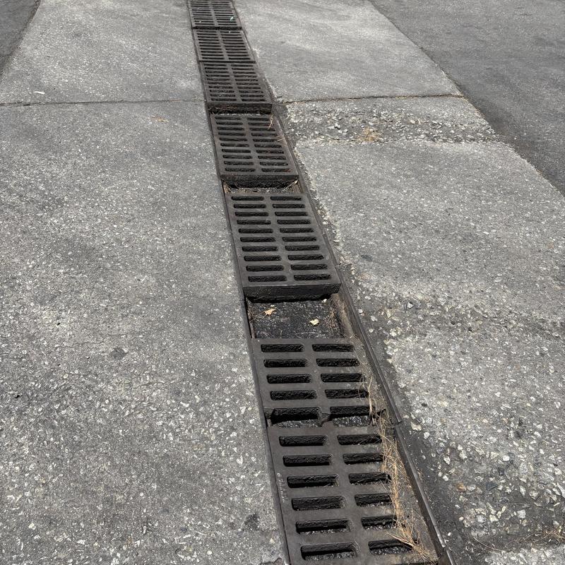 Linear drain with damaged metal grates on pavement Linear drain with damaged metal grates on pavement