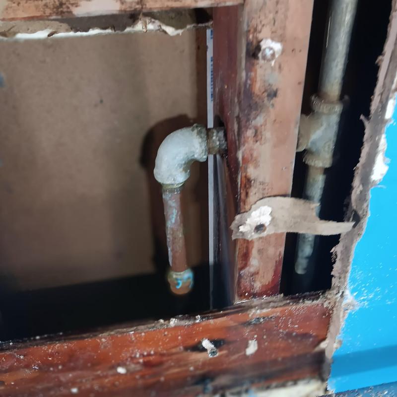 Copper hot water pipe inside wall with corrosion damage