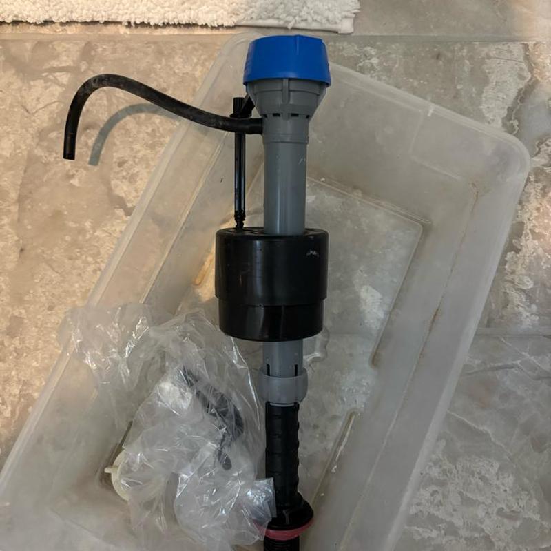 Toilet fill valve removed from tank, in container