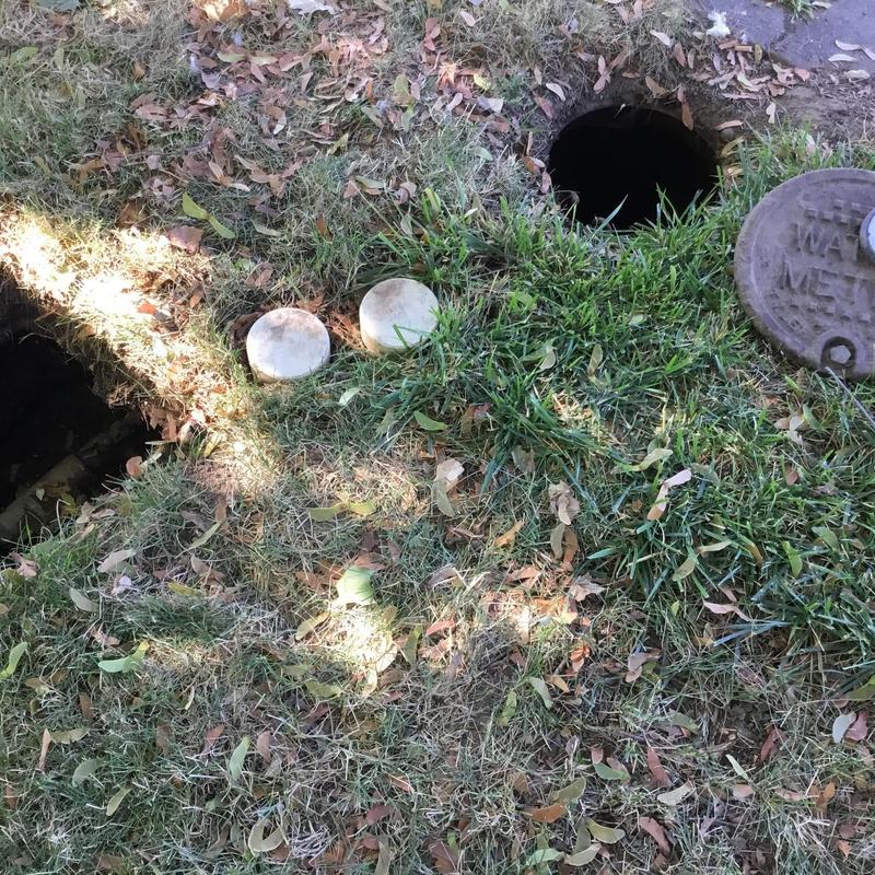 Water meter with open valve access hole in yard Water meter with open valve access hole in yard