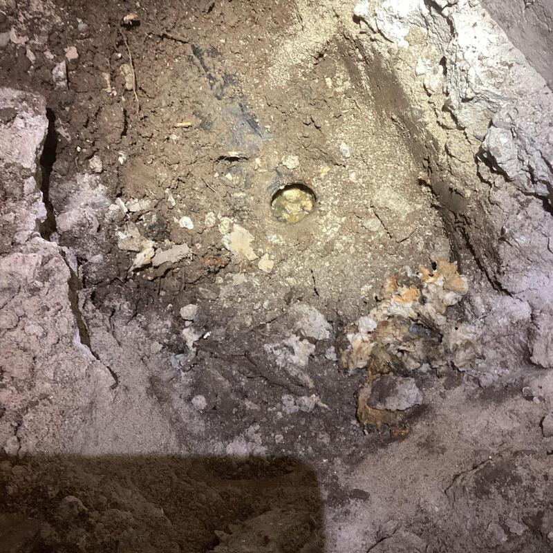 Concrete floor excavation exposing cast iron sewer line Concrete floor excavation exposing cast iron sewer line