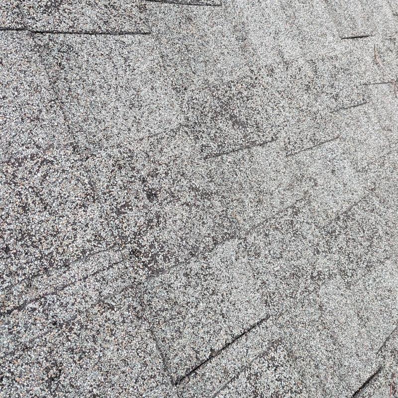 Asphalt roof shingles with heavy rain damage signs Asphalt roof shingles with heavy rain damage signs
