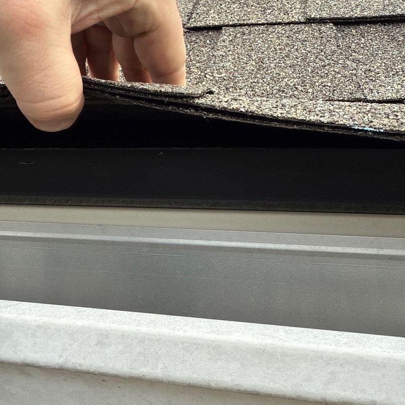 Roof shingles lifting inspection above gutter system