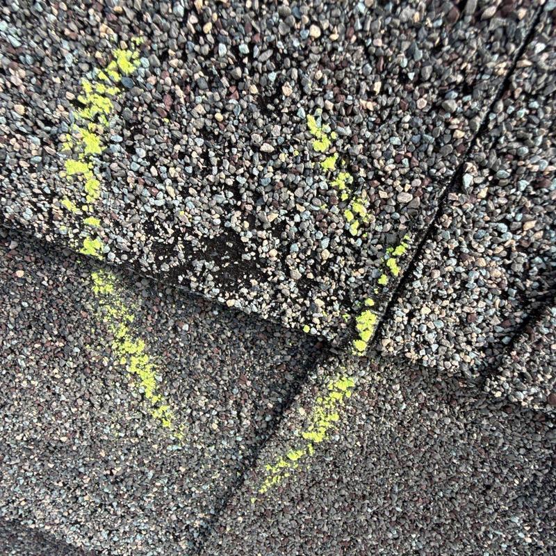 Asphalt shingles with hail damage marked in yellow