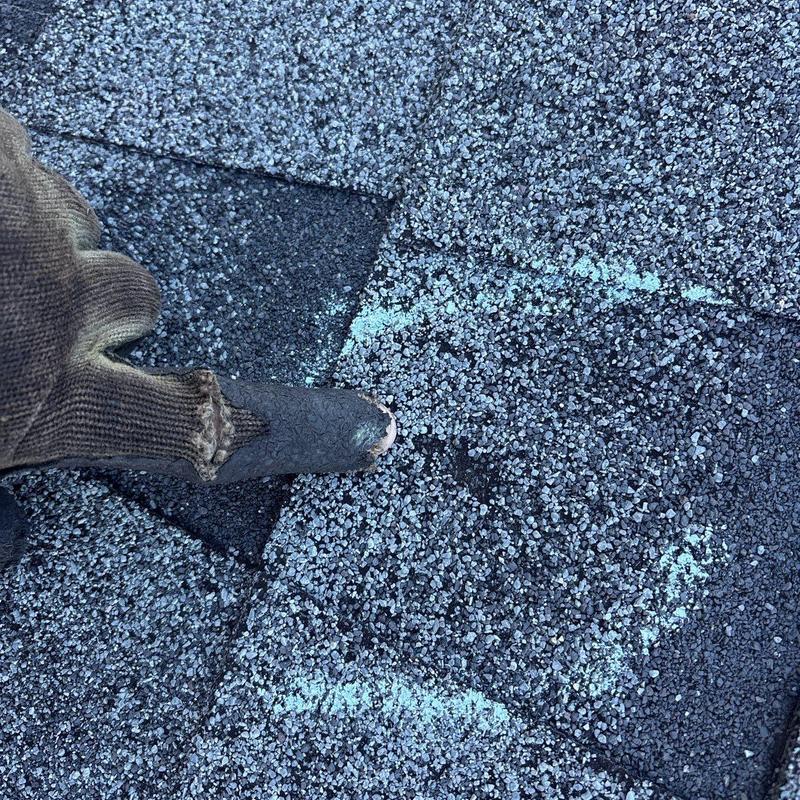 Asphalt roof shingle damage marked for repair