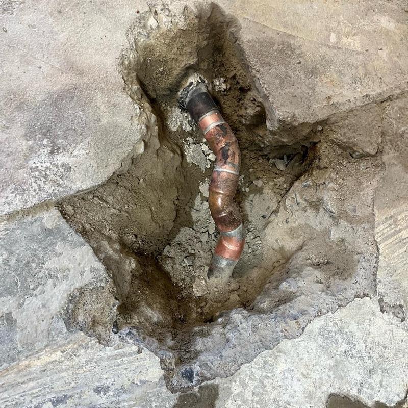 Copper refrigerant line exposed in concrete floor repair