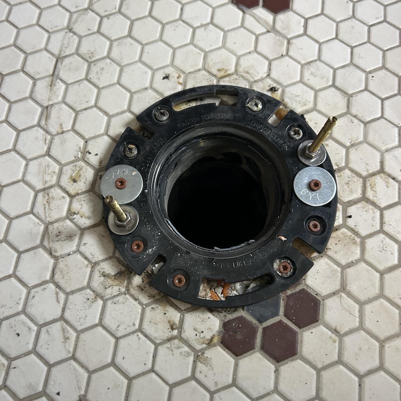 Toilet flange on hex tile floor with rusted screws Toilet flange on hex tile floor with rusted screws
