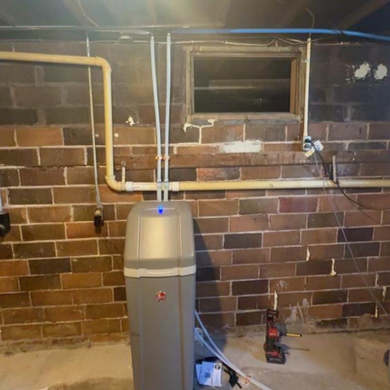 Water softener installation with connected pipes in basement