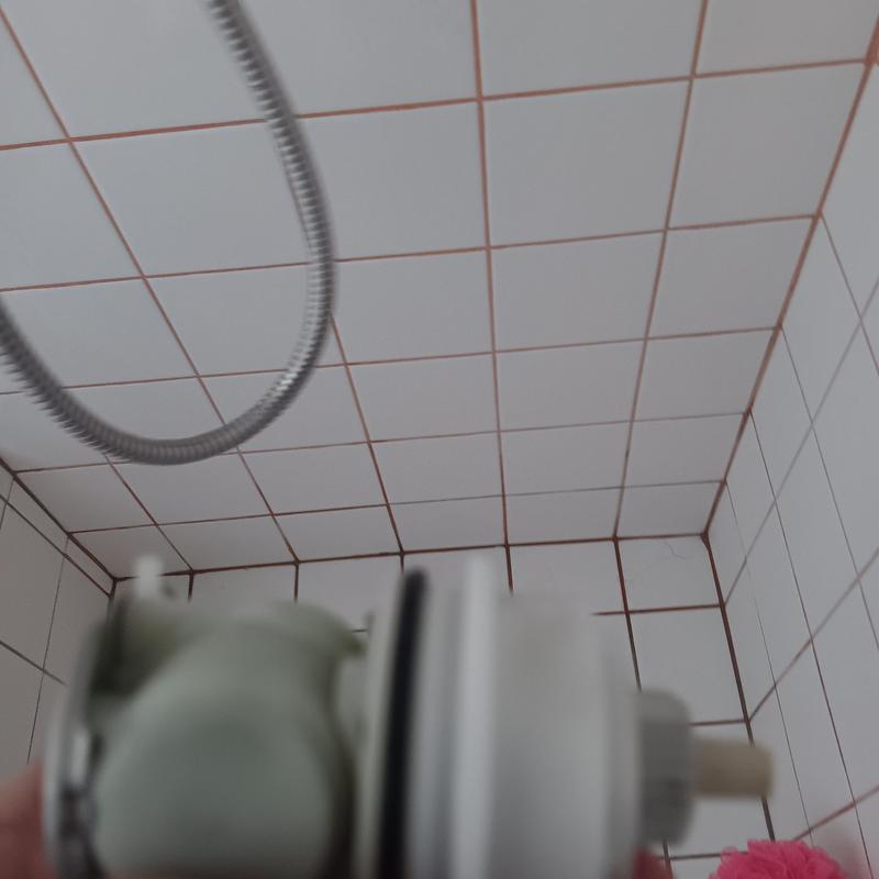 Shower valve cartridge held in bathroom with tiled walls