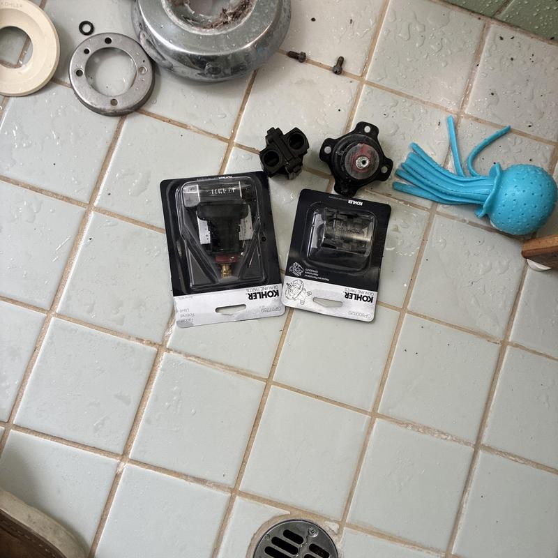 Kohler shower cartridges on tiled floor with tools