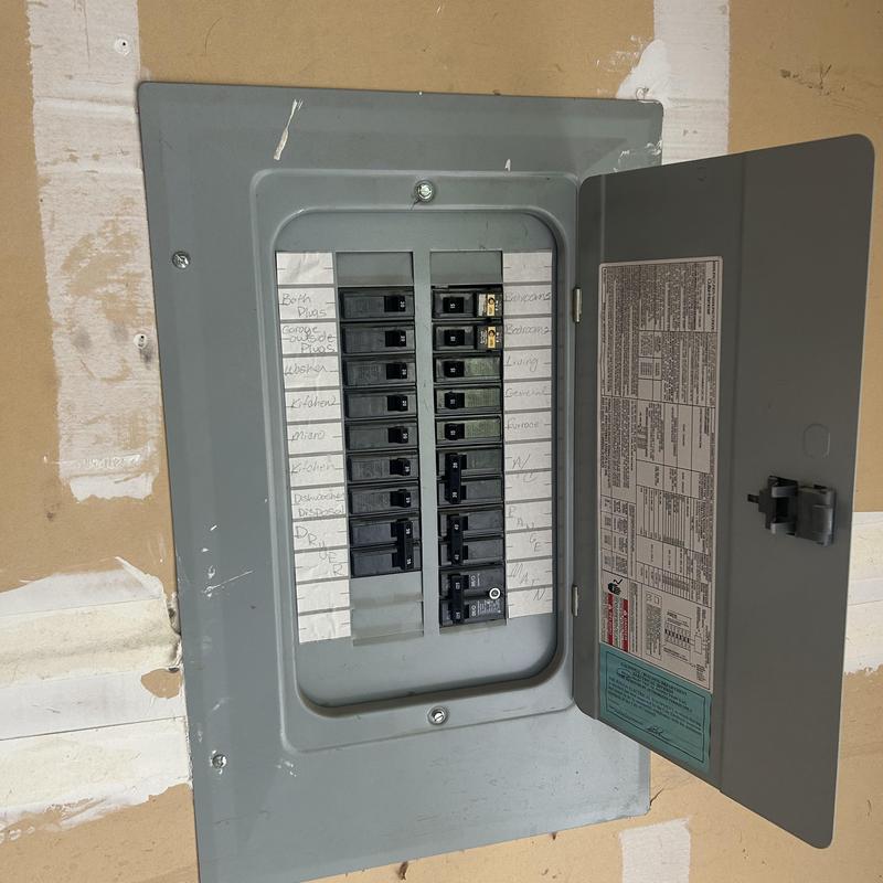 Electrical breaker panel with open door in garage wall Electrical breaker panel with open door in garage wall