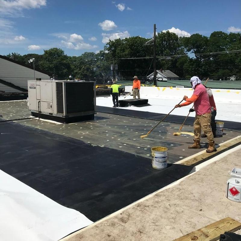 TPO roofing membrane installation with workers on flat roof TPO roofing membrane installation with workers on flat roof