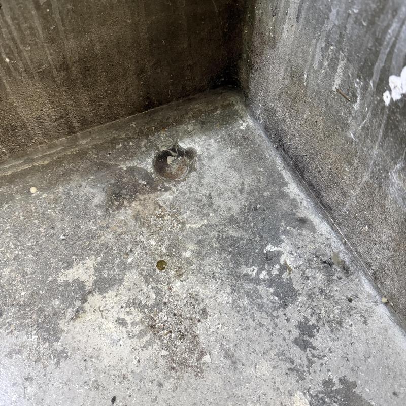 Drain stack with cleared clog in concrete floor corner