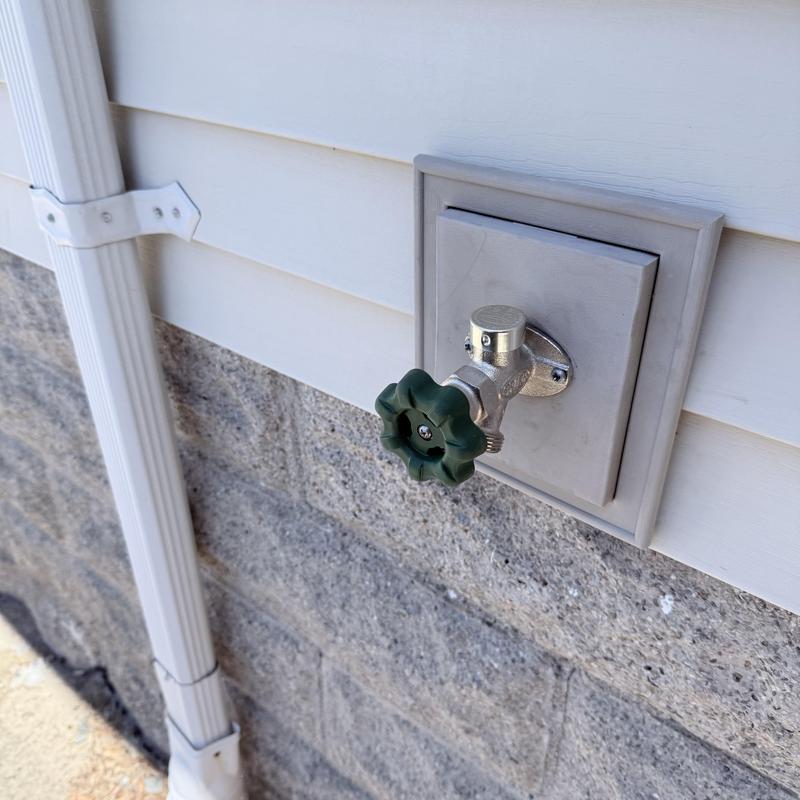 Silcock valve with green handle on house exterior
