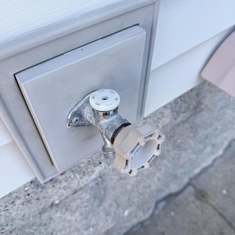Outdoor silcock valve with plastic handle on house exterior