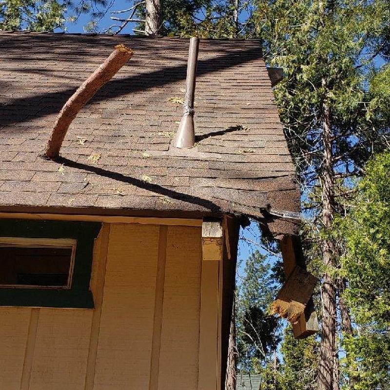 Asphalt shingle roof with storm damage on cabin corner