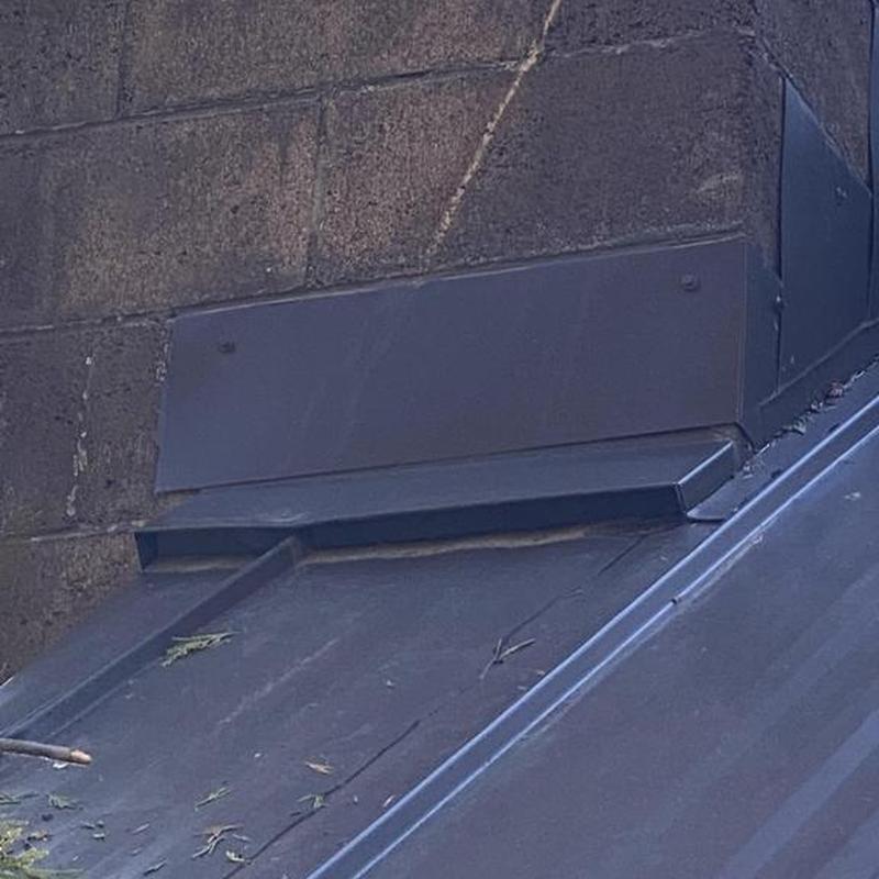 Metal roof flashing installation next to masonry wall