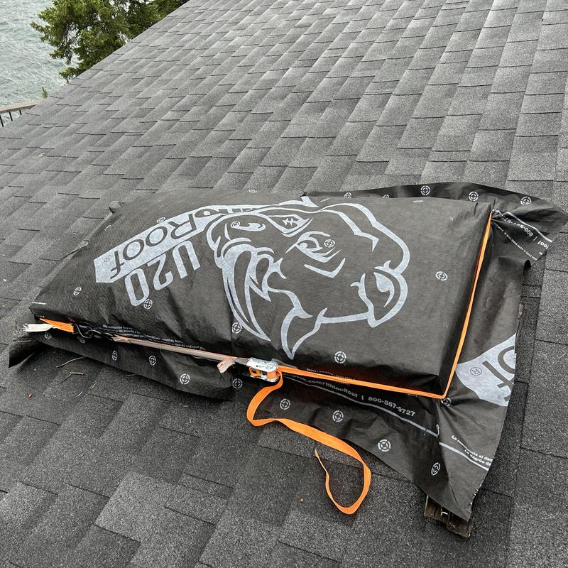 Skylight covered with protective tarp on shingled roof