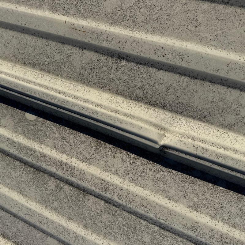 Metal roof panels with surface corrosion and dirt buildup
