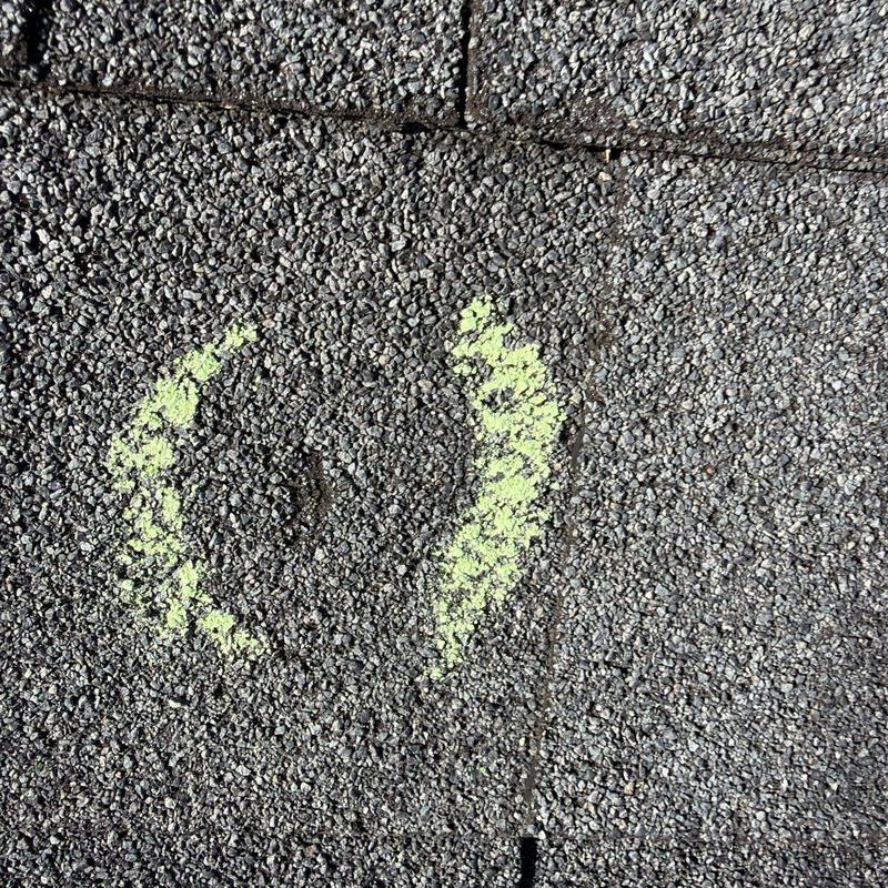 Roof shingles with hail damage marked in yellow chalk