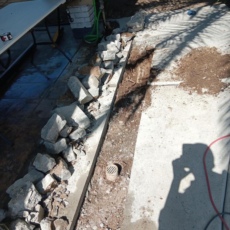 Area drain with broken concrete and excavation in backyard
