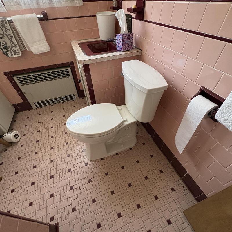 White toilet installation in pink tiled bathroom