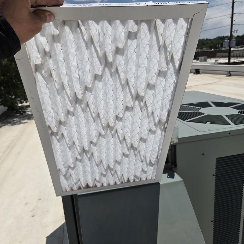 RTU air filter held by hand near rooftop unit RTU air filter held by hand near rooftop unit