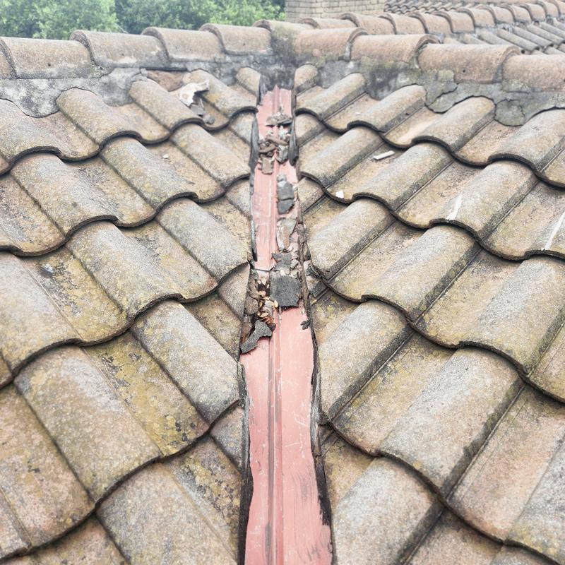 Tile roof valley with damaged flashing and debris Tile roof valley with damaged flashing and debris